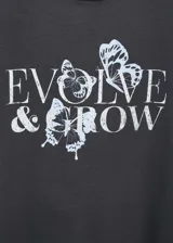 Camiseta de algodón color gris oscuro, con cuello redondo, mangas cortas y estampa frontal con la frase 'EVOLVE & GROW' acompañada de ilustraciones de mariposas.