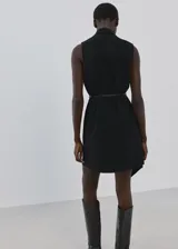 Vestido corto negro sin mangas, con cuello en V, diseño recto, bajo asimétrico y un fino cinturón incluido.