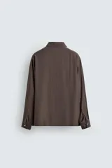 Camisa de corte relajado confeccionada en tejido fluido con mezcla de cupro, de manga larga con puños abotonados y cierre frontal de botones.