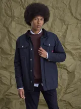 Campera de gabardina color azul marino, con cuello camisero, cierre frontal con botones metálicos y bolsillos frontales con solapa.
