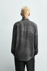 Camisa de corte relajado confeccionada en tejido fluido de viscosa, con cuello solapa, manga larga con puños abotonados y cierre frontal de botones. Presenta un estampado con efecto lavado.