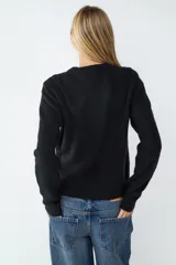 Sweater de manga larga confeccionado en tejido de punto suave, con diseño clásico de cuello redondo y terminaciones acanaladas en puños y bajo.