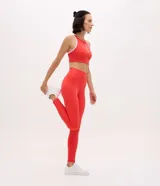 Pantalón legging deportivo de tiro alto, confeccionado en microfibra elástica de color rojo. Presenta un diseño ajustado al cuerpo con costuras reforzadas que brindan soporte y libertad de movimiento.