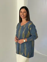 Sweater de punto color azul jean con estampado de pinceladas doradas brillantes, cuello en V y mangas largas.