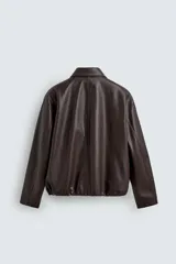 Cazadora de corte relajado confeccionada en tejido efecto piel color marrón oscuro. Presenta cuello solapa, cierre frontal con cremallera oculta por solapa con botones a presión, bolsillos de plastrón con solapa en la parte frontal y bajo ajustable con elástico en los laterales.