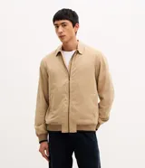 Campera bomber masculina de sarga color beige, con cuello inglés, cierre frontal de cremallera, bolsillos y elásticos en puños y cintura.