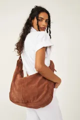 Bolso tote de ante suave, de cuerpo blando estilo hobo, con asa larga para el hombro y cierre superior con cremallera.