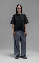 Pantalón deportivo de corte regular confeccionado en microfibra opaca, con cintura elástica y puños ajustables en los tobillos. Presenta vivos laterales a contratono que recorren toda la pierna y un pequeño parche con logo en el frente.