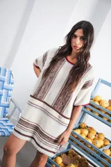 Vestido corto tejido a rayas horizontales en tonos beige y blanco, con cuello redondo y mangas cortas.