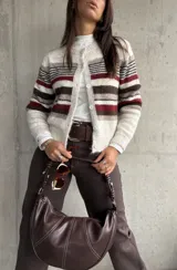 Cardigan de punto con diseño a rayas horizontales en tonos crema, marrón y bordó. Presenta cuello redondo, cierre frontal con botones y mangas largas.