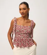 Blusa peplum de viscosa y lino con estampado floral rojo y blanco. Cuenta con escote recto, tirantes anchos con lazos para atar en los hombros y bajo con volado fluido.