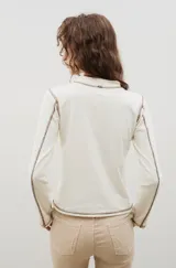 Remera de cuello alto y manga larga en color crudo, con costuras a la vista en contraste de color marrón.