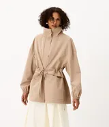 Campera cortaviento oversized color beige, de cuello alto, mangas largas con puños elásticos, bolsillos frontales con solapa y cordón ajustable en la cintura.