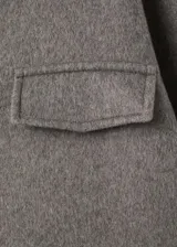 Chaqueta estilo overshirt de paño color gris, con cuello solapa, cierre frontal de botones oscuros, bolsillos con solapa en el pecho y bolsillos aplicados en la parte inferior.