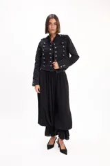 Chaqueta de jean estilo napoleónico color negro, con cuello mao, hombreras y filas dobles de botones metálicos grabados.