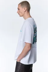 Remera blanca de corte holgado, con cuello redondo y diseño de manga corta. Cuenta con un pequeño estampado tipográfico en color verde en el pecho.