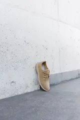 Zapatilla de diseño minimalista confeccionada en lana merino, con cordones al tono y suela de EVA. Presenta un estilo atemporal y versátil, ideal para uso diario.