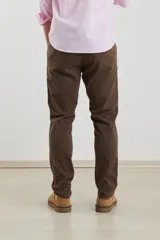 Pantalón de vestir verde oliva, de corte slim fit, sin pinzas, con bolsillos laterales y traseros. Se ajusta a la cintura con cinturón de cuero marrón.