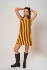 Vestido corto tejido a rayas verticales color amarillo y marrón, con escote redondo y mangas sisa. Incluye cinturón marrón con hebilla dorada.