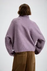 Jersey de punto con cuello alto y cierre frontal de cremallera metálica, de manga larga con puños ajustados y diseño holgado.