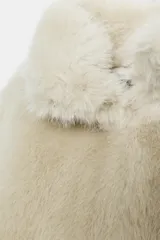 Abrigo corto de pelo sintético color crudo, con cuello subido, manga larga y bolsillos laterales ocultos en la costura. Cierre frontal con gancho metálico y forro interior a tono.