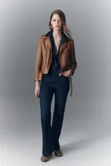 Campera estilo biker confeccionada en cuero ovino, con solapas amplias, charreteras en los hombros y cinturón ajustable en la cintura. Presenta cierres metálicos en el frente y bolsillos laterales, con forro interior de poliéster.