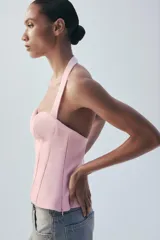 Top negro con estampado de lunares blancos, escote halter y diseño estructurado tipo corset con copas fruncidas en el centro.