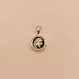 Dije circular de plata 925 y oro, con centro de piedra ónix negra y detalle de trébol de cuatro hojas en relieve en el centro.