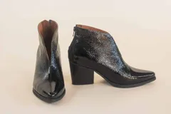Botinetas negras de cuero charol, con corte en V en el empeine y taco geométrico.