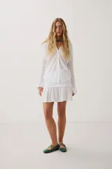 Camisa blanca de manga larga con cuello en V y cierre frontal de botones.