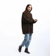 Buzo unisex de tejido de punto grueso en lana merino, color rojo, con cuello redondo y diseño de calce relajado. Presenta un detalle bordado a mano en contraste en la manga.