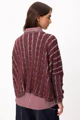 Sweater de punto con diseño de rayas verticales en relieve y textura trenzada, color terracota y beige. Presenta cuello redondo, corte holgado y diseño cropped.