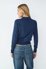 Sweater de punto color gris con cuello estilo polo, cierre frontal con botones y mangas largas.