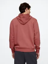 Canguro con cierre frontal y capucha, color rojo lavado, con el logo de la marca estampado en el pecho en color azul marino. Presenta bolsillos tipo canguro y puños acanalados.