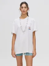 Remera de corte cuadrado y ajuste holgado, color verde oliva, con pequeño estampado gráfico de un velero en el pecho y etiqueta decorativa en la manga.