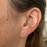 Aros pequeños de plata 925 con acabado en oro 18k, con forma de tres flores con circonias.
