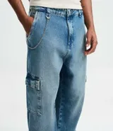 Pantalón de jean corte baggy con diseño cargo, bolsillos laterales amplios y cadena metálica desmontable en la cintura. Presenta un lavado clásico y ajuste tradicional.