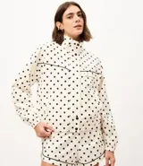 Campera rompeviento deportiva Get Over de microfibra, con estampado de lunares, cuello alto, cierre frontal oculto, bolsillos delanteros con ribete oscuro y puños elásticos.