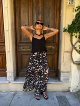 Falda larga de tela estampada con flores y hojas en tonos marrones, negros y violetas. Tiene elástico en la cintura.