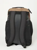 Mochila de color marrón claro y negro, con múltiples bolsillos frontales con cierre y logo de Rusty en negro. Presenta paneles laterales de malla negra y asa superior.