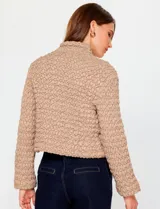 Campera de mujer color azul marino, con textura capitoneada de efecto burbuja o nido de abeja. Presenta cuello alto con cierre frontal y corte recto y corto.