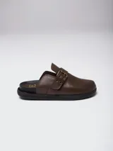 Zuecos de cuero color suela con diseño de punta redonda y ajuste mediante una tira con hebilla metálica en el empeine. Presentan una suela plana de goma negra y plantilla interior con logo grabado.