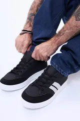 Championes urbanos de estilo deportivo, color negro con detalles en blanco en los laterales y suela blanca. Presentan puntera reforzada en material tipo gamuza y cierre mediante cordones.