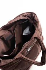 Bolso tipo shopper acolchado color negro, con diseño de cuadrícula. Posee dos asas de hombro y un parche ovalado con un logo estilizado en el frente.