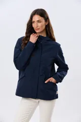 Campera liviana con capucha, de corte clásico, color beige, con bolsillos laterales con solapa y cierre frontal.