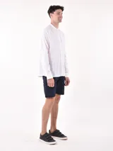 Camisa negra de manga larga con cuello mao y botones blancos frontales.