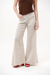 Pantalón color beige de corte wide leg, con bolsillos delanteros y cierre frontal de botón y cremallera.