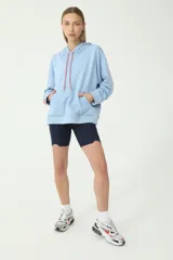 Buzo hoodie celeste de rústico, con capucha y cordones de ajuste color salmón y verde. Tiene etiqueta de la marca en la manga derecha con logo Basset 00'S.