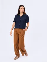 Camisa azul marino de manga corta, con cuello solapa y cierre frontal de botones claros. Confeccionada en mezcla de viscosa, poliamida y lino.