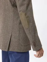 Blazer de tweed color azul marino con coderas en contraste, cierre frontal de botones y bolsillos laterales. Presenta un diseño clásico de corte regular.